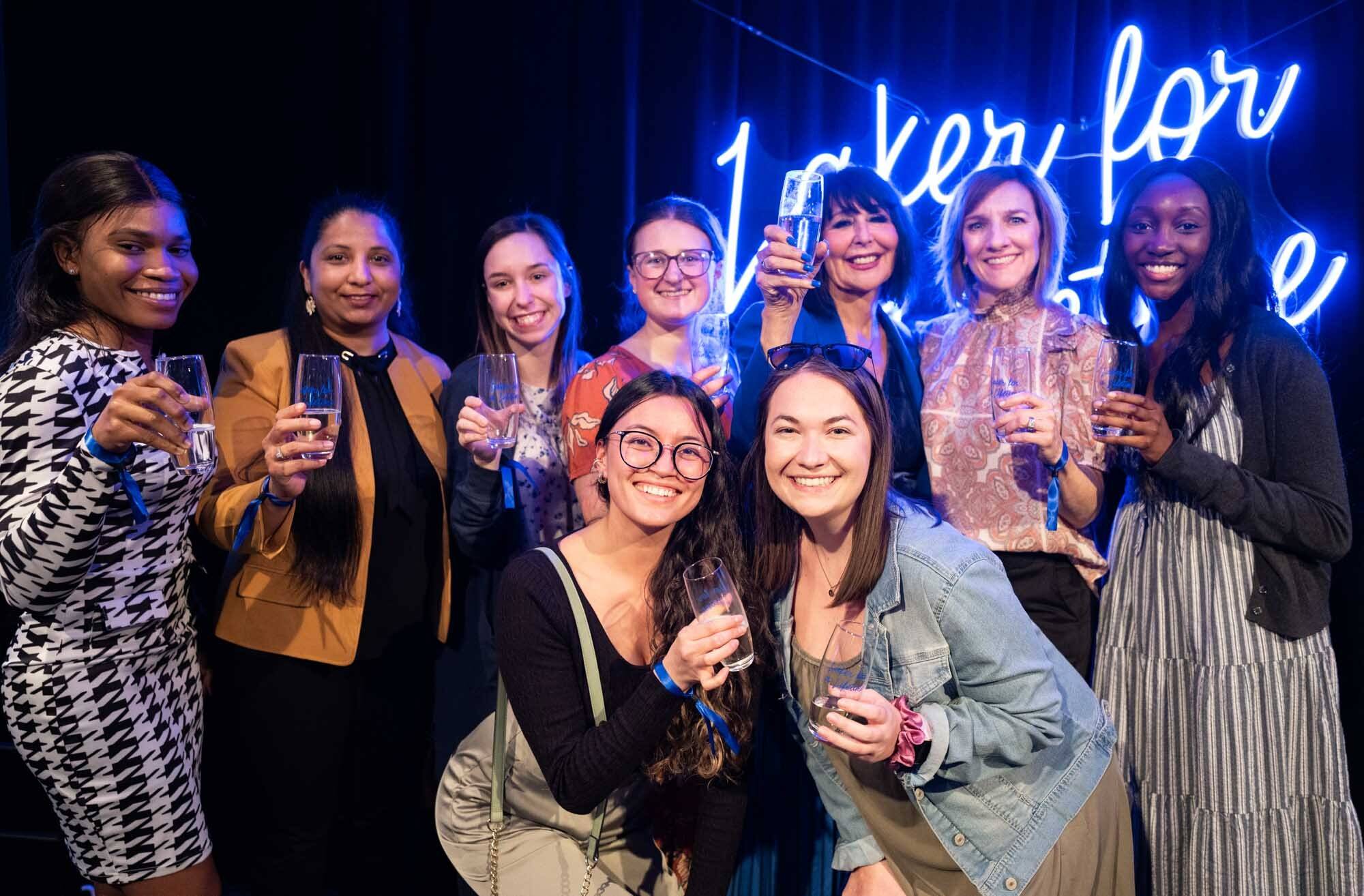 Eight graduates pose for a photo at a Toast event
